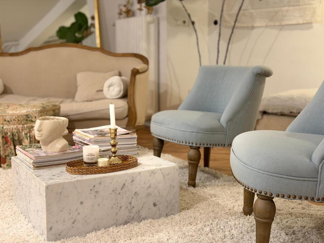 Living room with sofa, two chairs, and marble table.
