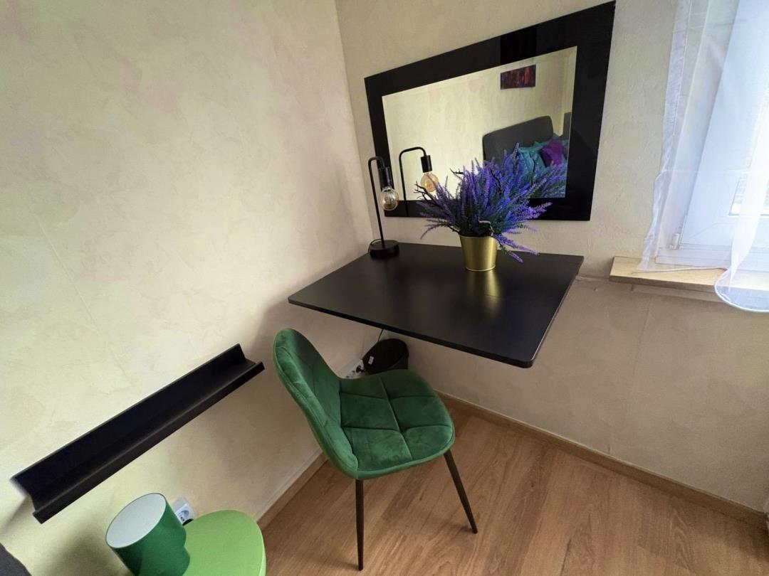 Desk with green chair and mirror on the wall