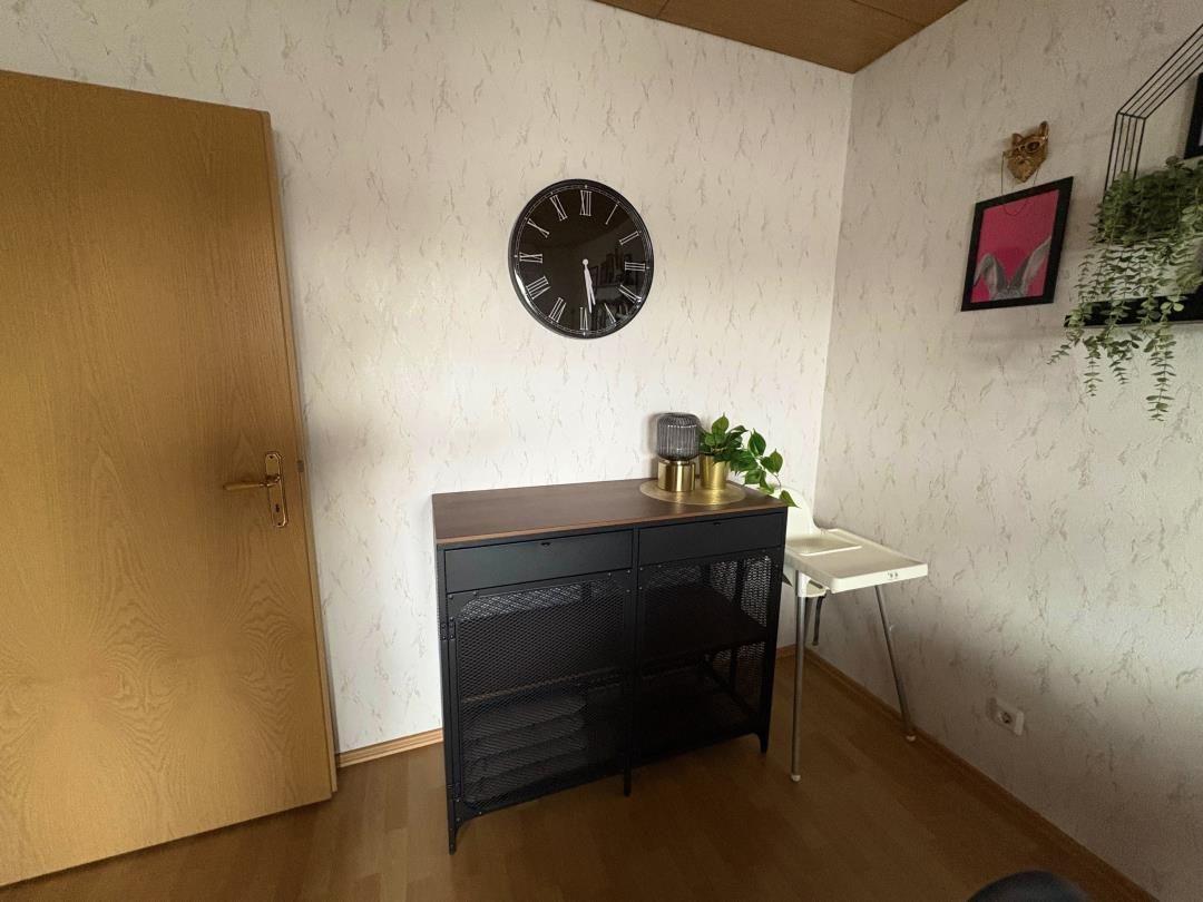 Entrance area with cabinet, clock, and plants on the wall.