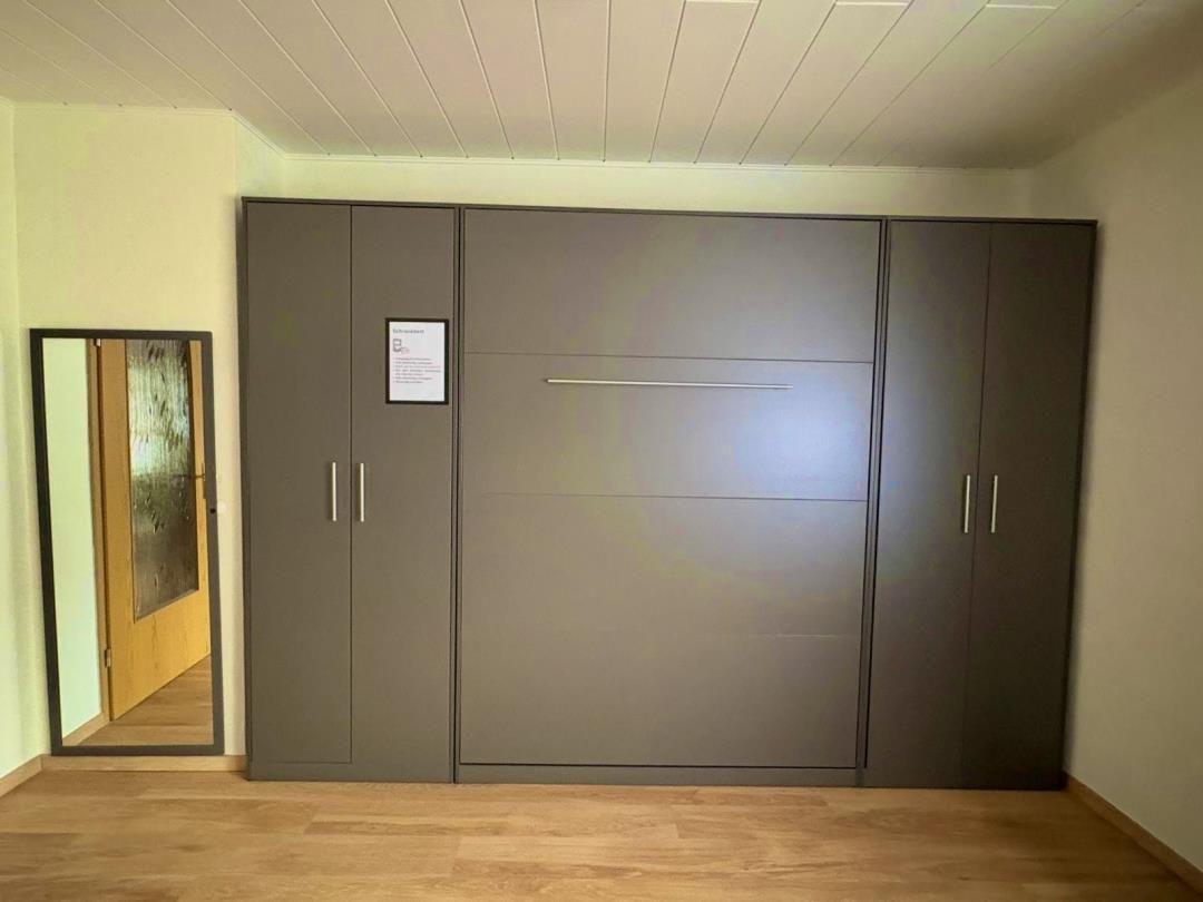 Bedroom with integrated wardrobe and mirror on the wall.