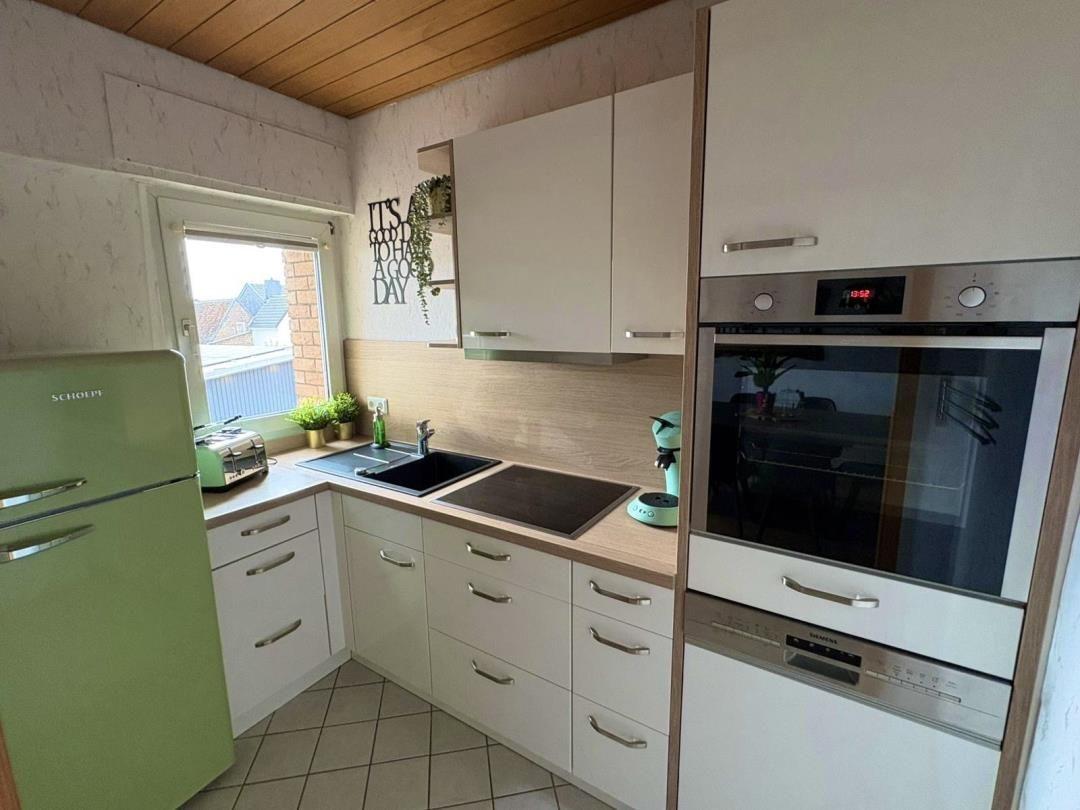 Kitchen with white cabinets, green refrigerator, and built-in oven.