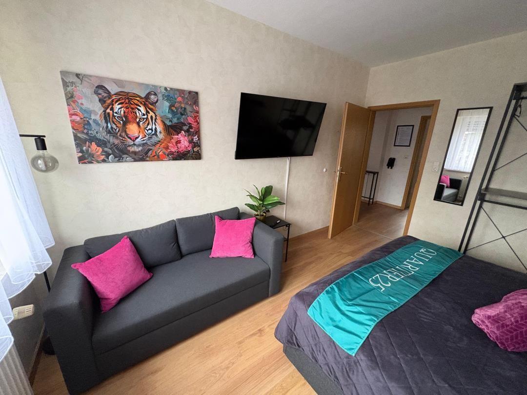 Room with sofa, bed, and wall art of a tiger.