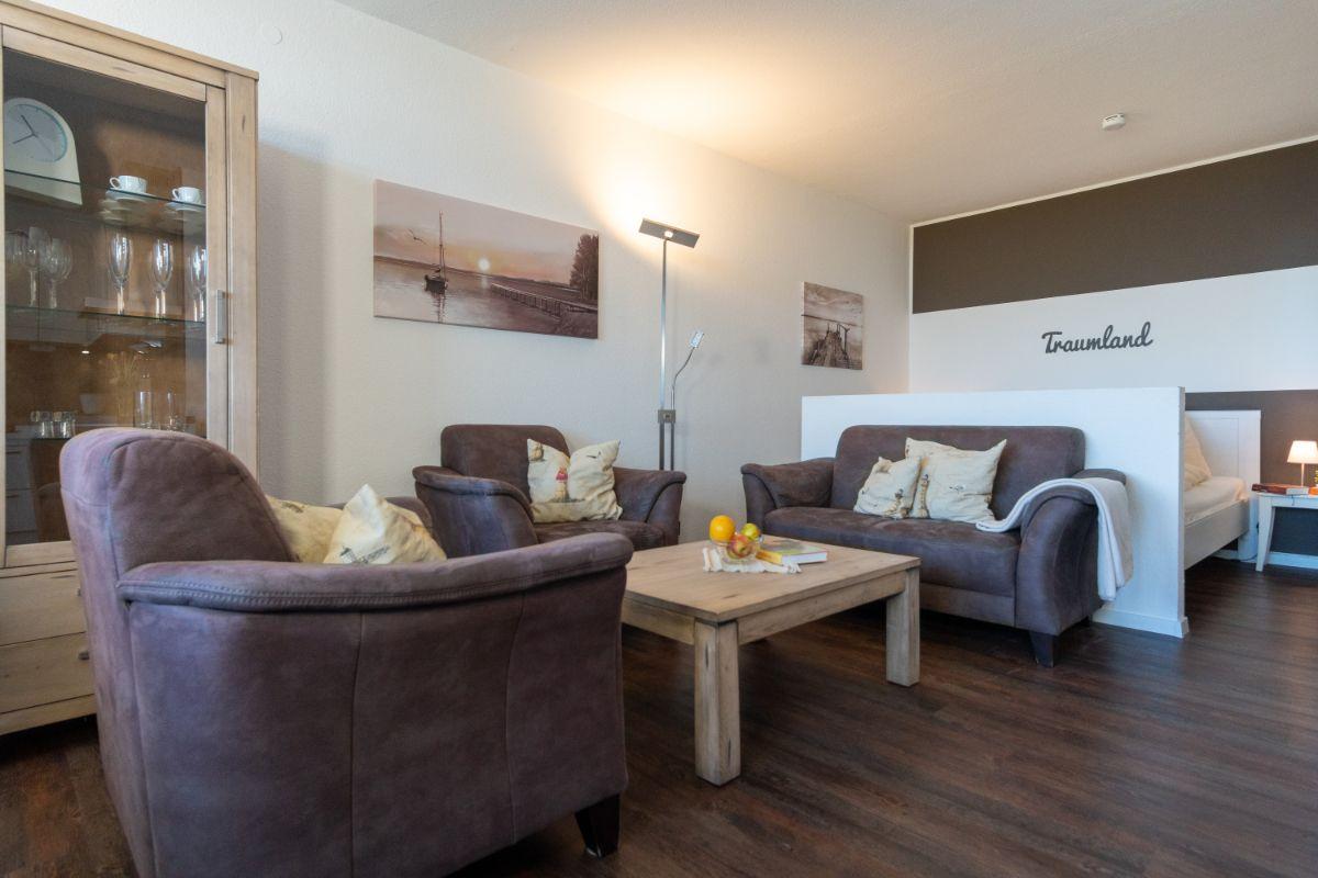 Wohnzimmer mit Sofa, Sessel und Tisch. Hintergrundbild an der Wand.