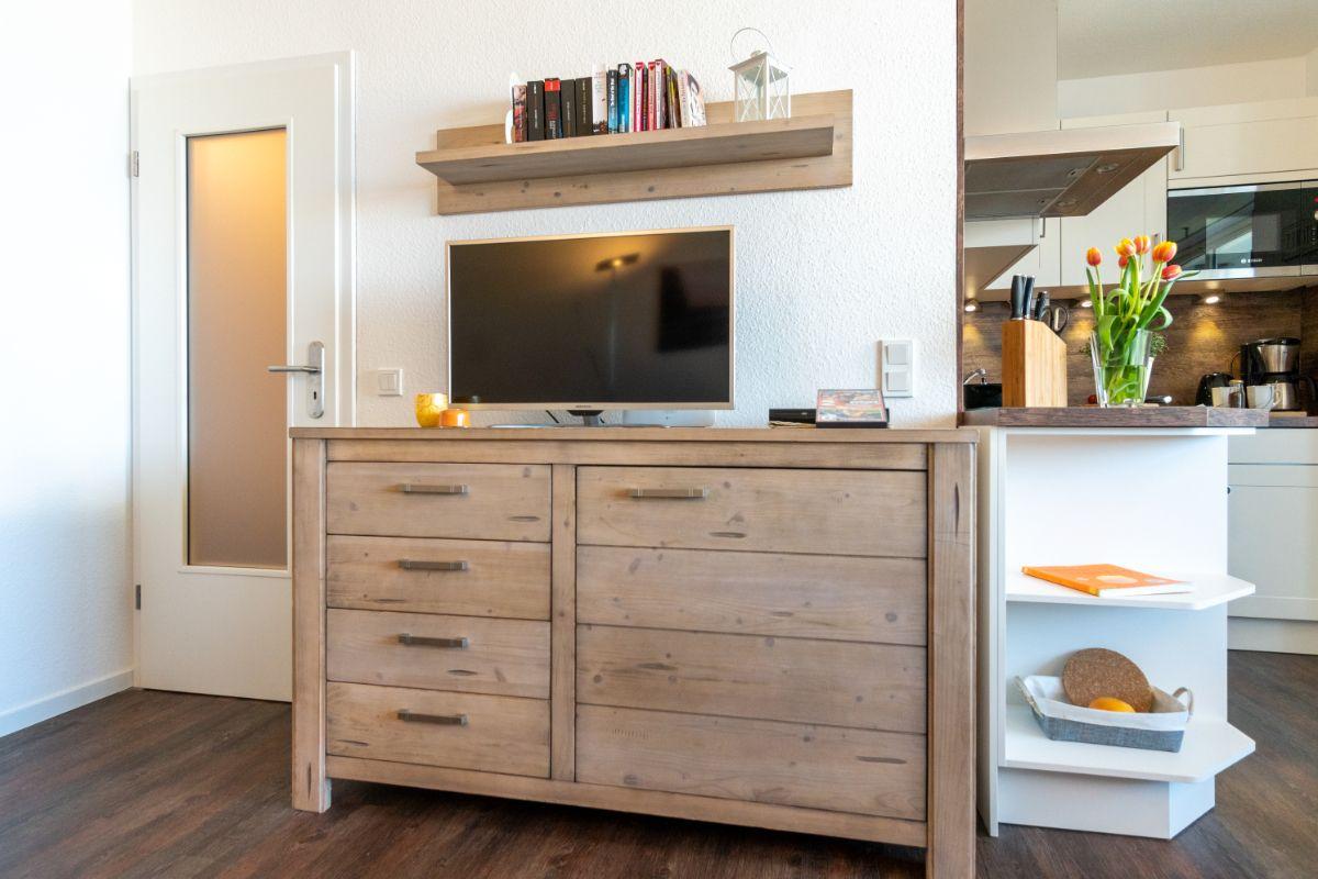 TV auf Holzschrank, Küchenbereich mit Blumen und Kochutensilien