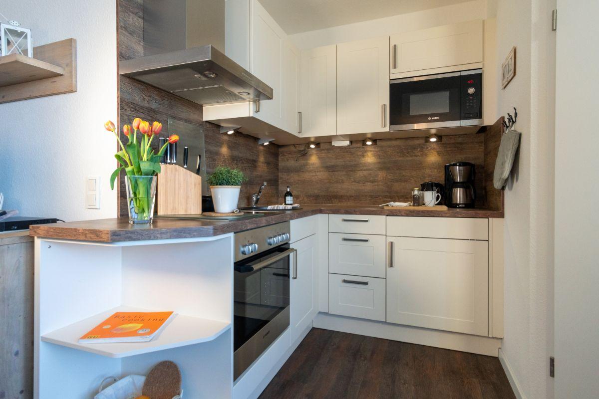 Küche mit weißen Schränken, Holzoberfläche und integriertem Herd.