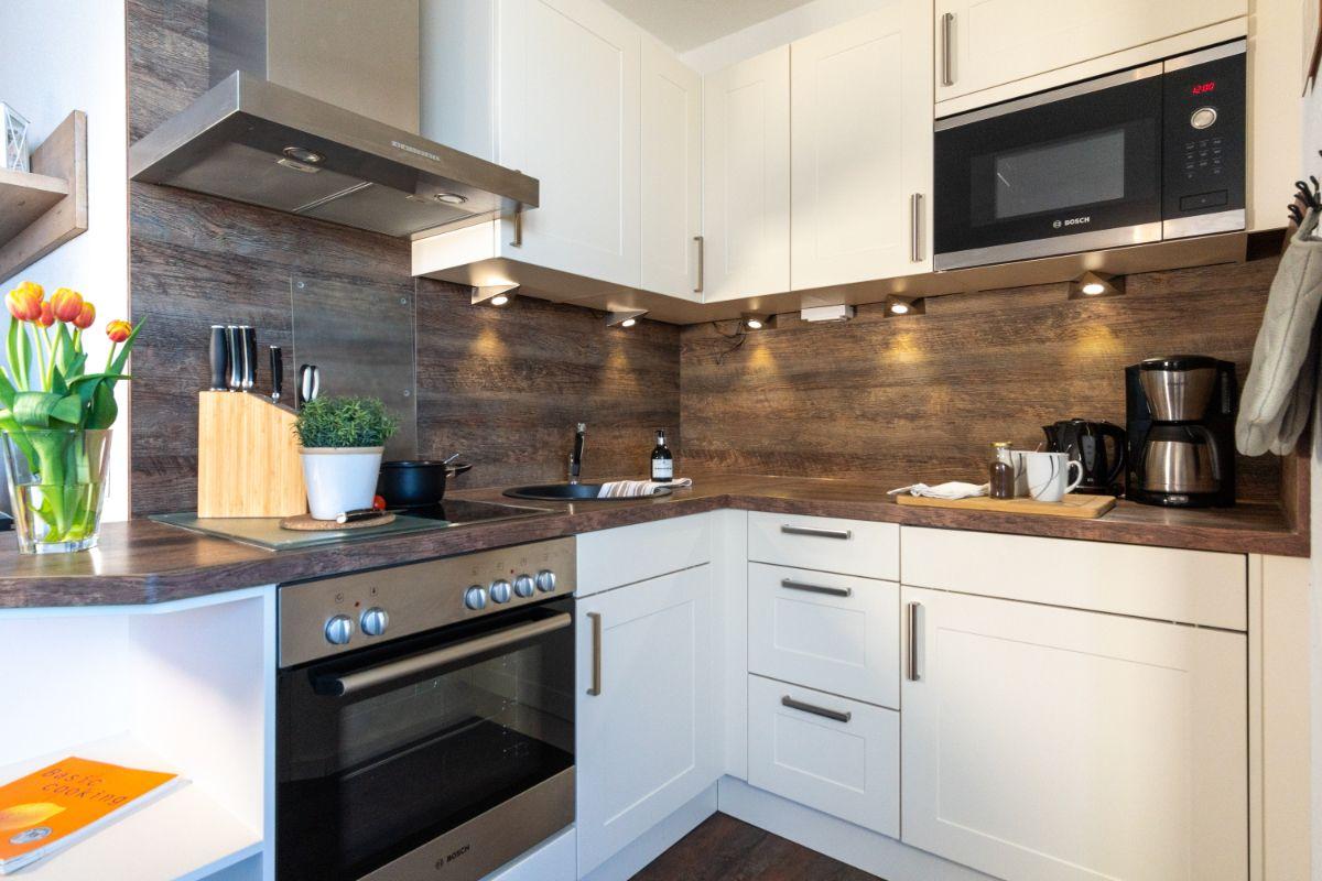Küche mit weißen Schränken, Holzoberfläche und Bosch-Geräten.