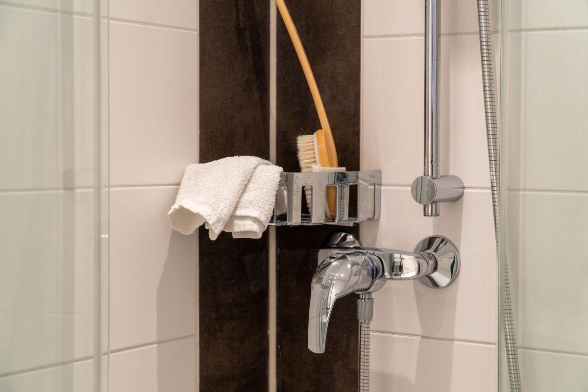 Dusche mit Duschbrause, Handtuch und Bürste an der Wand