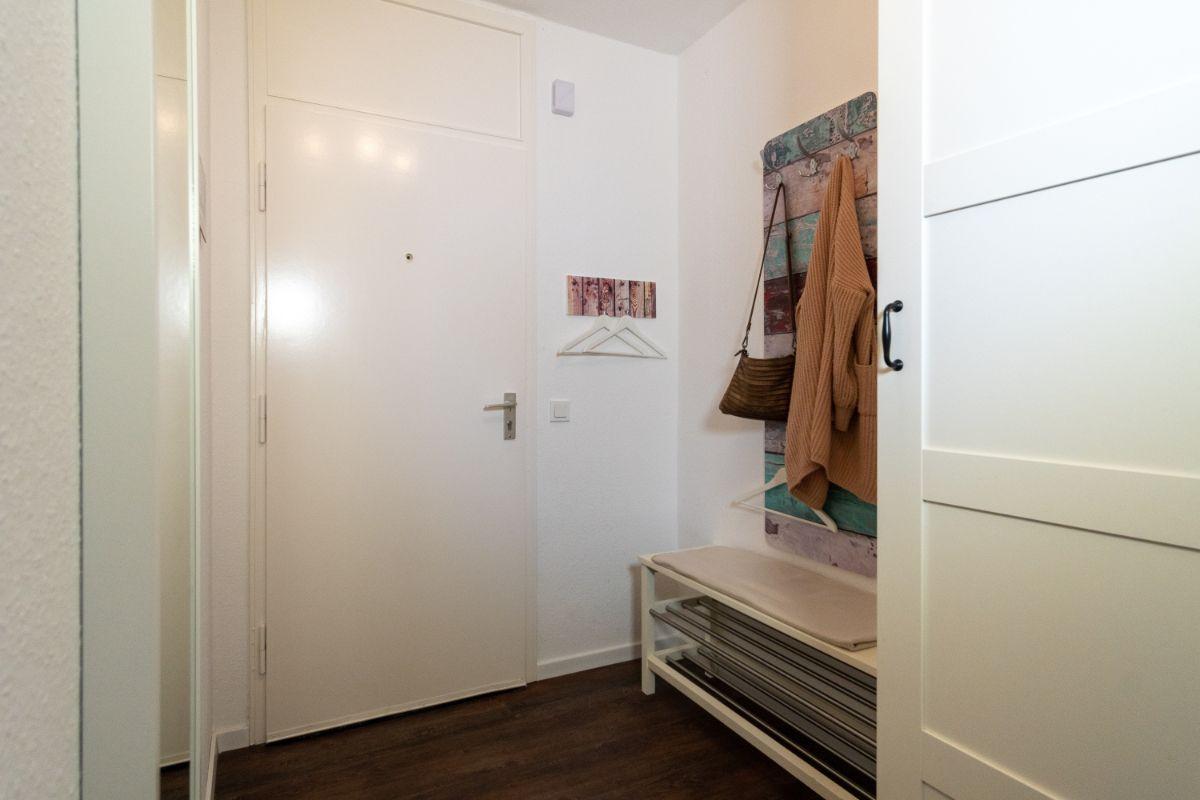 Eingangsbereich mit Schuhschrank, Haken und Kleidungsstücke.