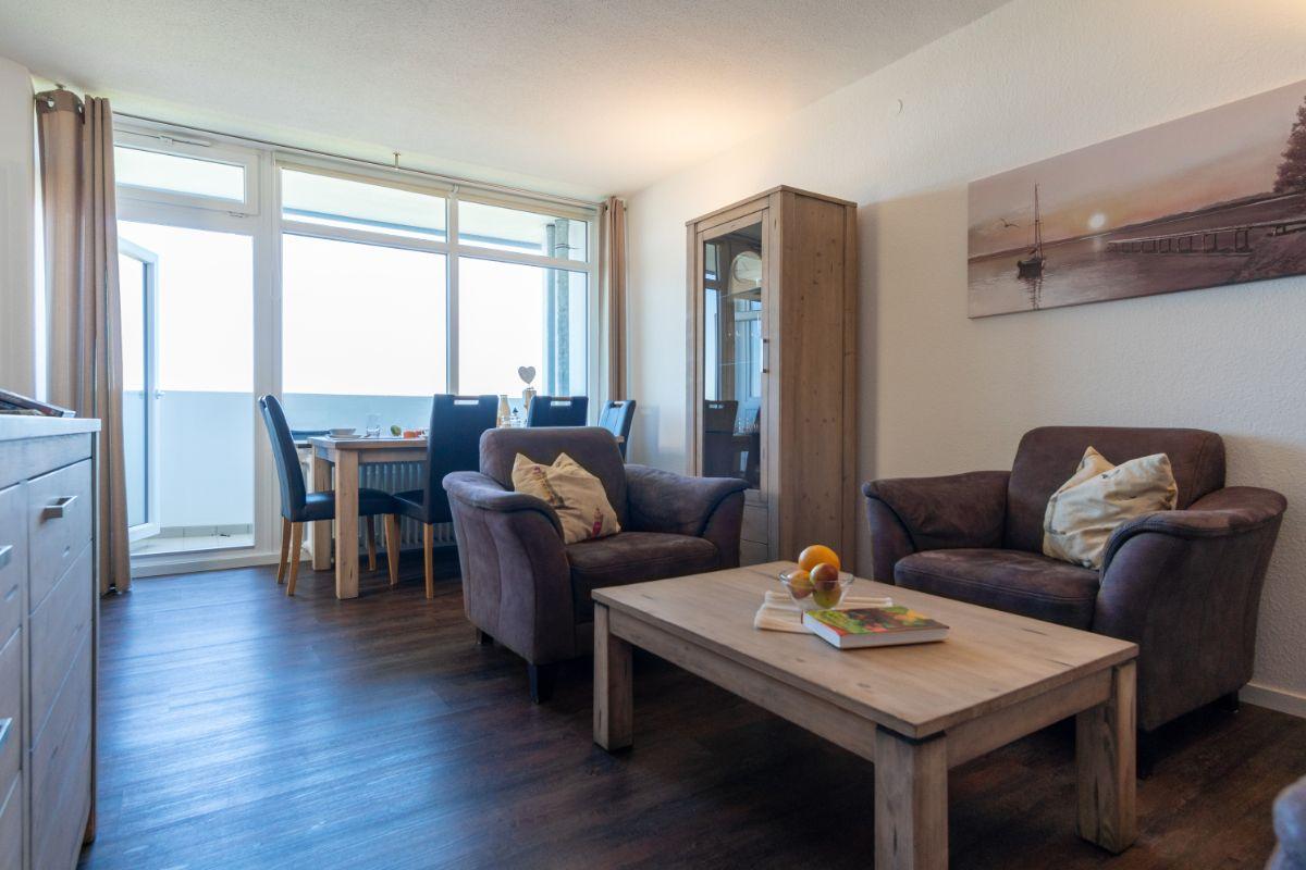 Wohnzimmer mit zwei Sesseln, Tisch und Blick auf Balkon.