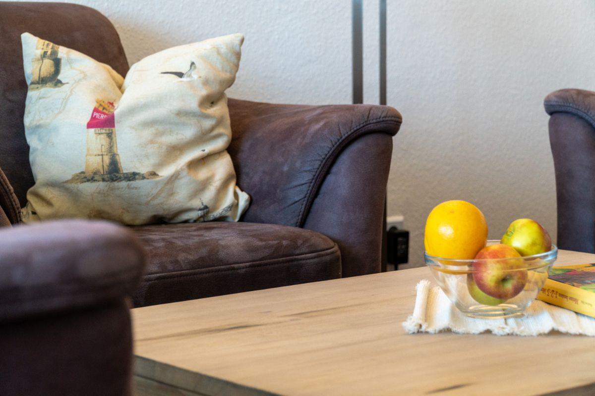 Ein braunes Sofa mit Kissen und Obst auf einem Tisch.