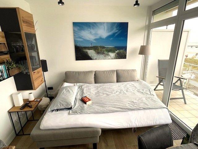 Schlafzimmer mit Bett, Wandbild und Balkonzugang.