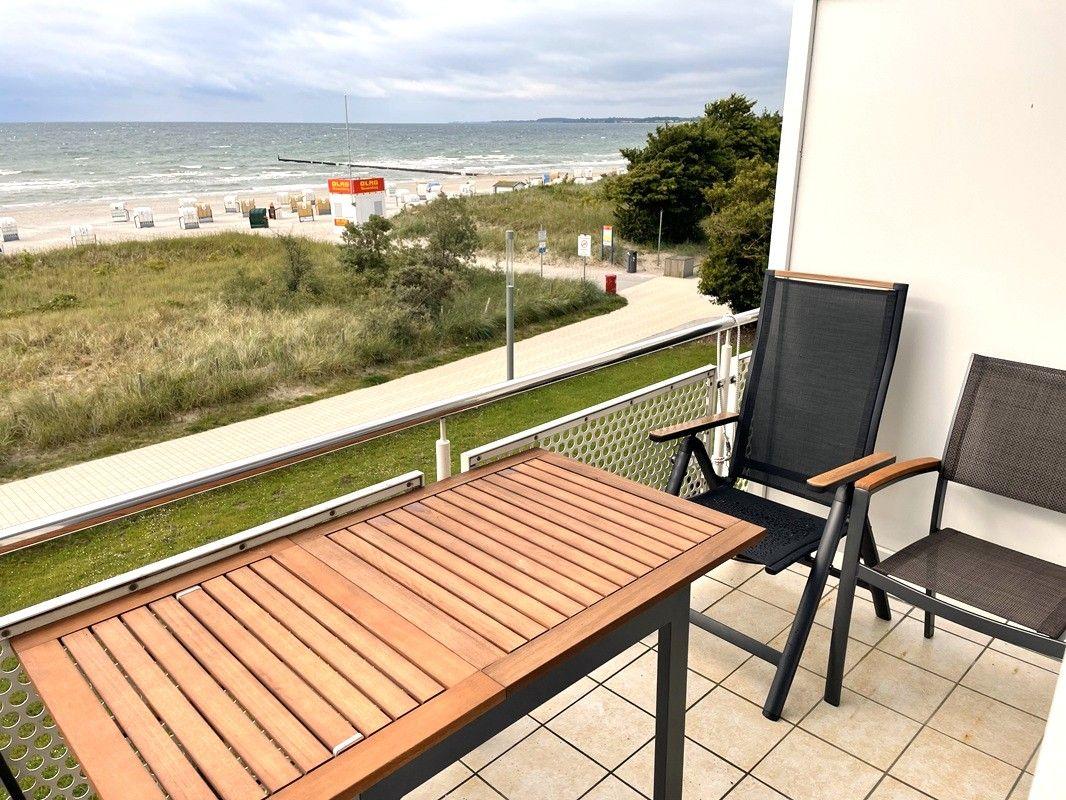 Terrasse mit Tisch und Stühlen. Blick auf Strand und Meer.