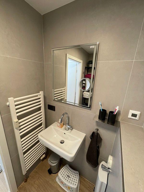 Badezimmer mit Waschbecken, Spiegel und Heizkörper.
