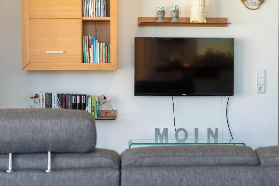 Wohnzimmer mit Sofa, Fernseher und Bücherregal an der Wand.