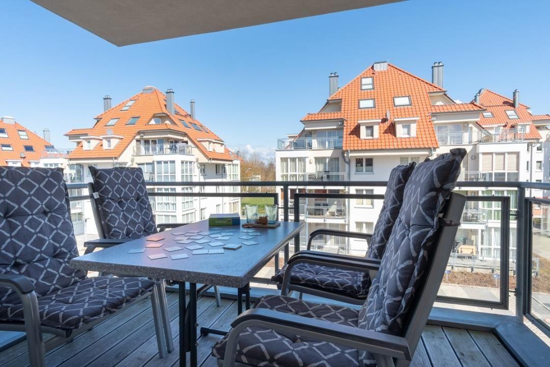 Terrasse mit Tisch und Stühlen, Blick auf Wohnhäuser mit roten Dächern.