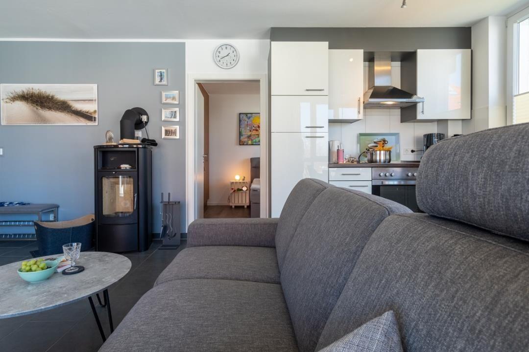 Wohnbereich mit Sofa, Küche und Kaminofen