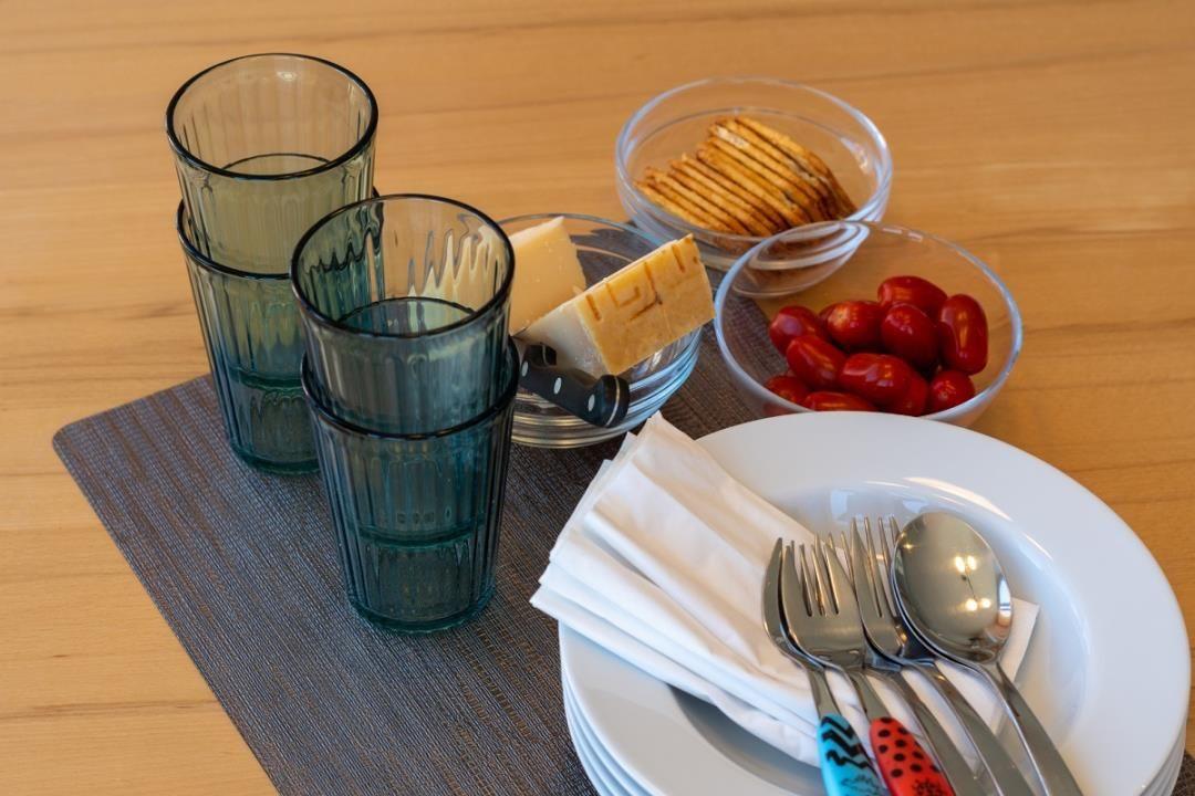 Tisch mit Gläsern, Käse, Crackern und Tomaten auf Untertasse mit Besteck.