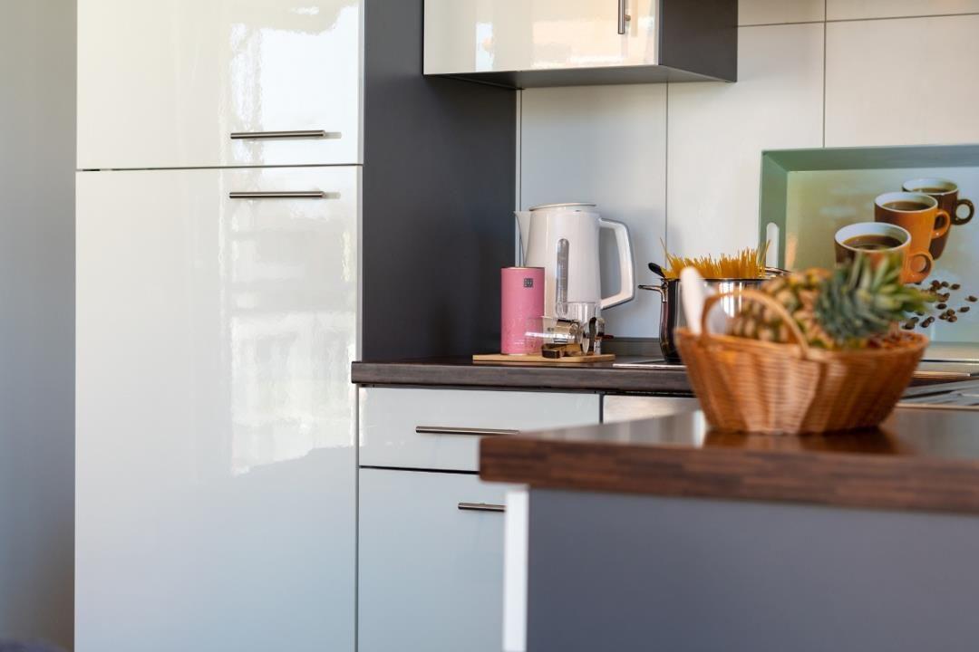 Küche mit weißen Schränken, Kaffeekanne und Korb mit Früchten.