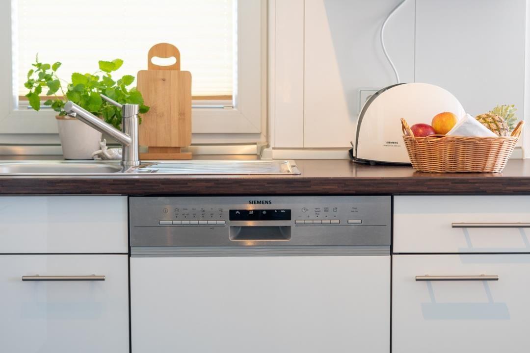 Küche mit Spüle, Waschmaschine und Korb mit Obst.