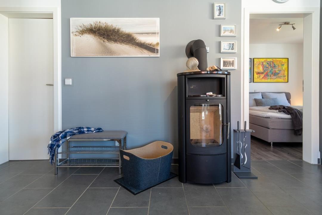 Eingangsbereich mit Kaminofen, Bank und Kunstwerken an der Wand.