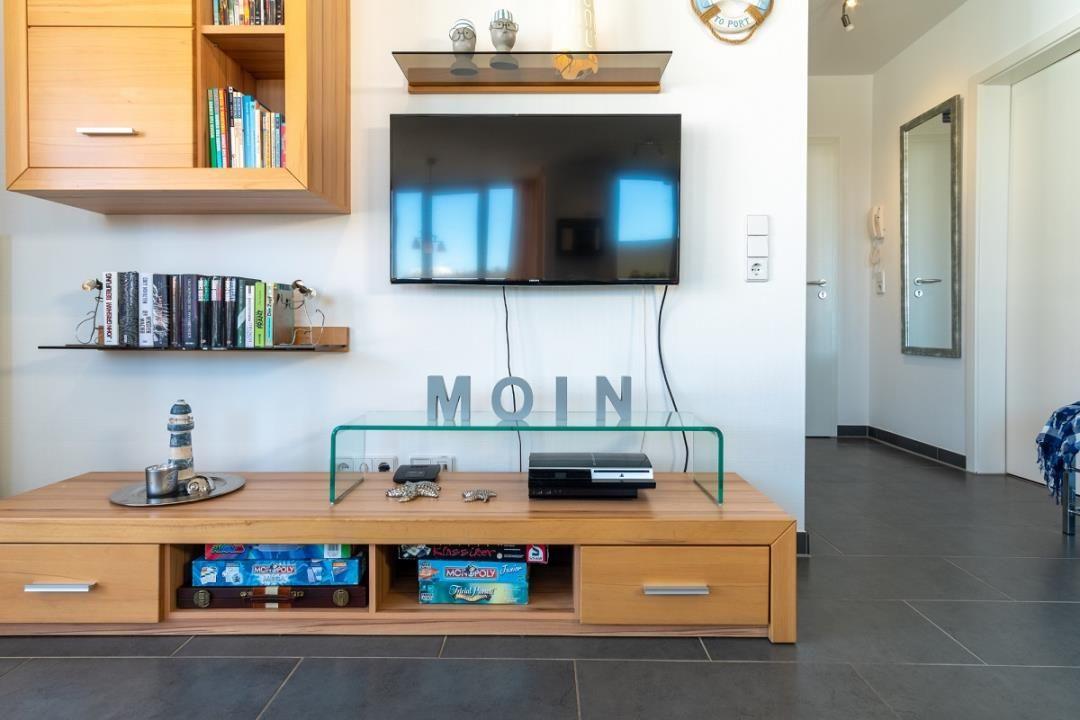 Wohnzimmer mit Fernseher, Holzmöbel und Regalen mit Büchern.