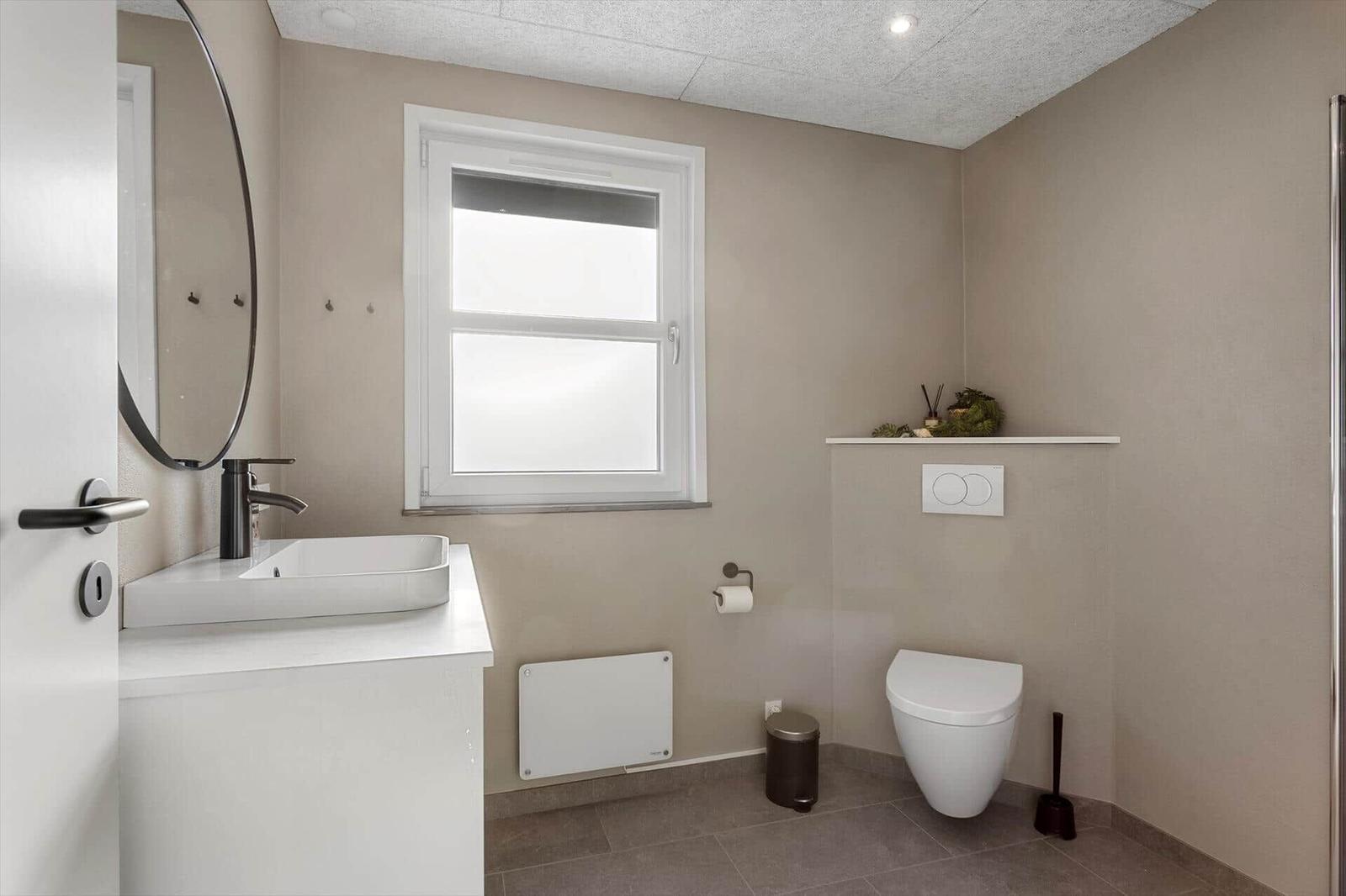 Bathroom with sink, toilet, and window.