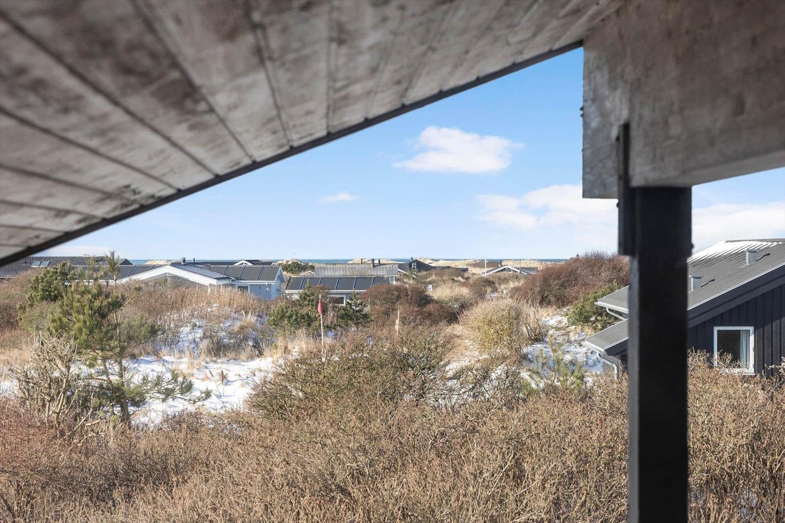 View from balcony over dune protection with houses and sea