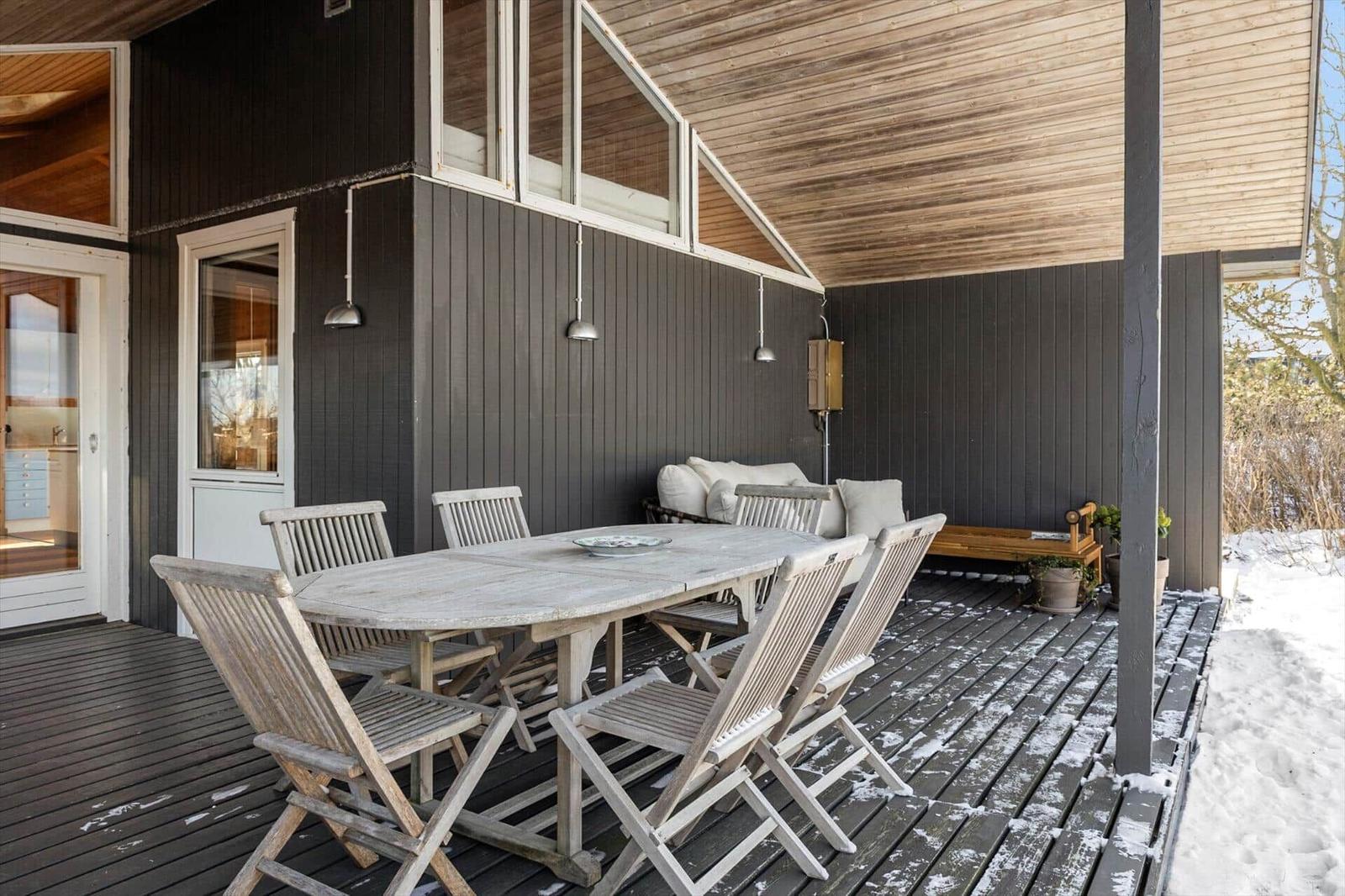 Deck with wooden table, chairs, and sofa under roof