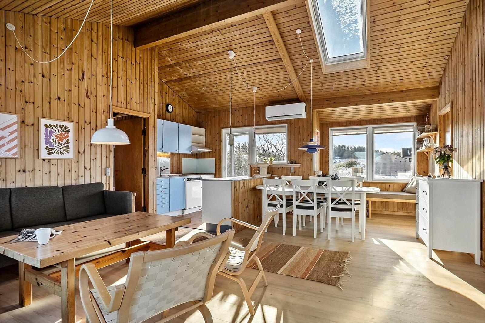 Living kitchen with wooden walls, dining area, and view of the landscape.