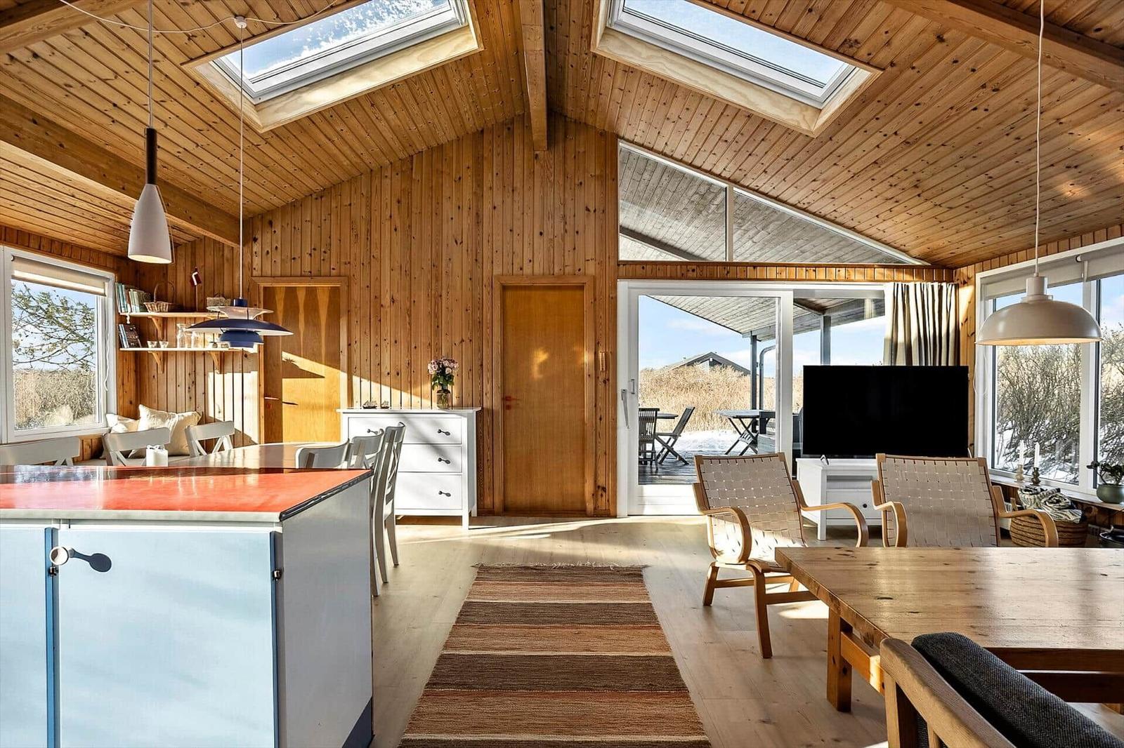 Living space with wooden walls, windows, and kitchen island.
