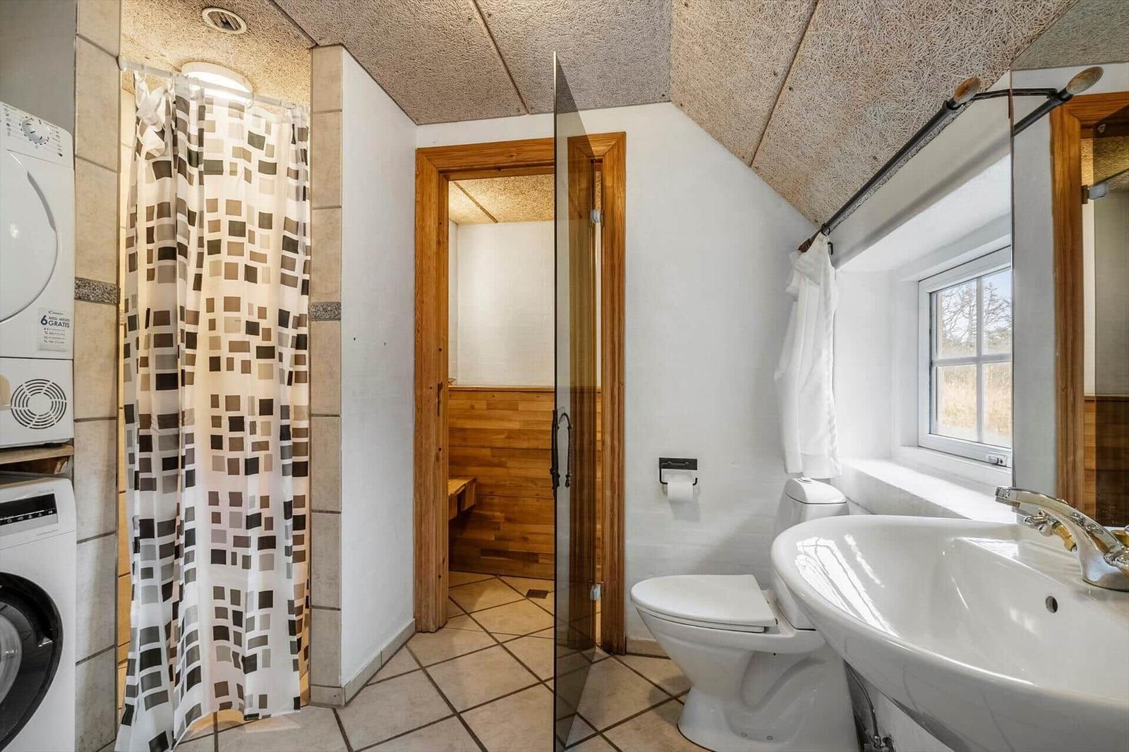 Badezimmer mit Dusche, Toilette, Waschbecken und Sauna.