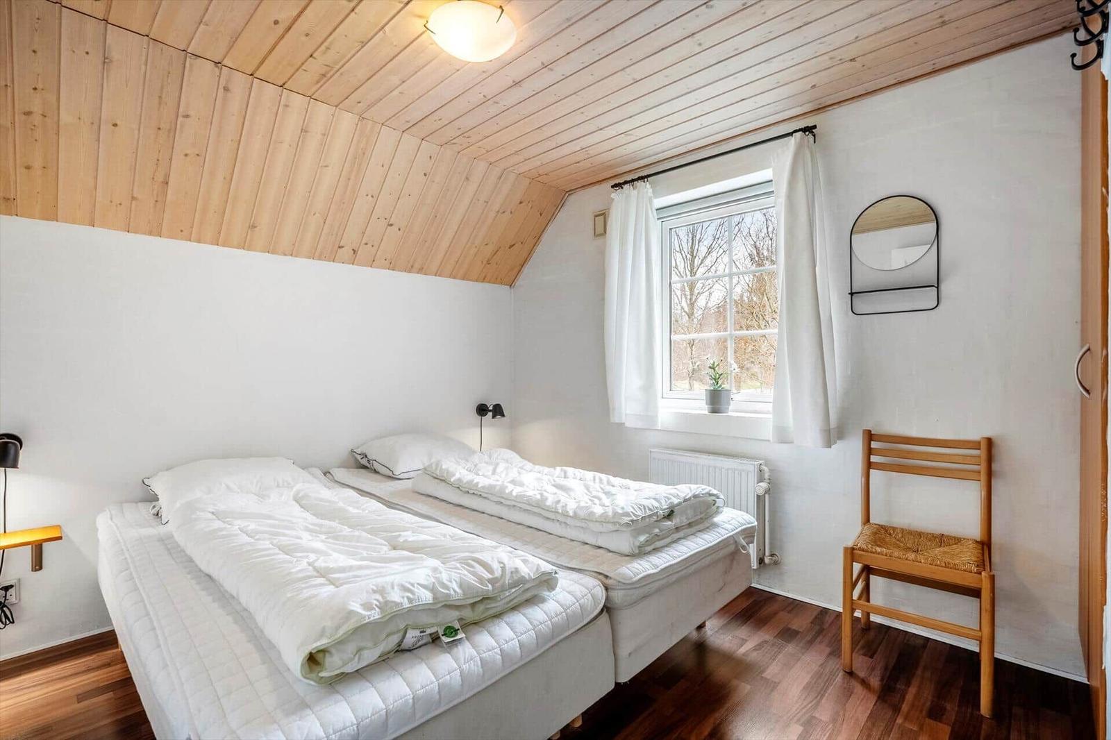 Zimmer mit zwei Betten, Holzdecke und Fenster mit Blick nach draußen.