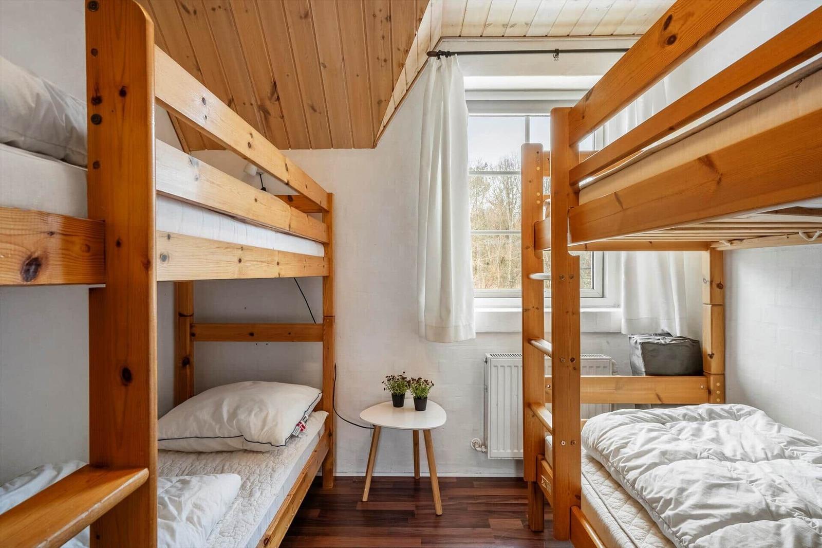 Zwei Holzbetten mit Fenster und kleinem Tisch.
