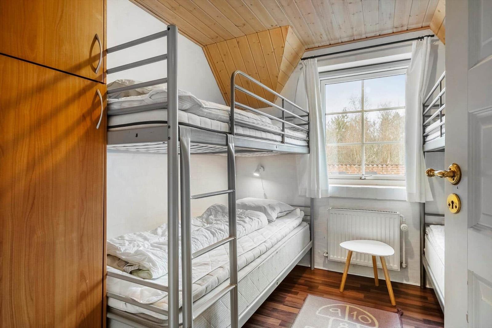 Zimmer mit Kletterbetten, Holzdecke und Fenster mit Blick auf Außengelände.