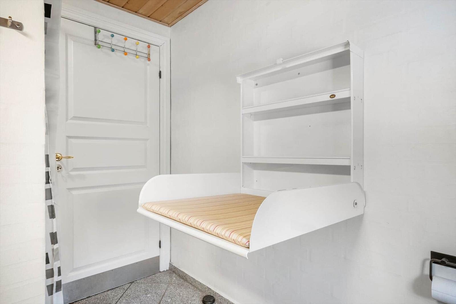 Wandbett mit Matratze und Regal an der Wand. Tür mit bunten Haken.
