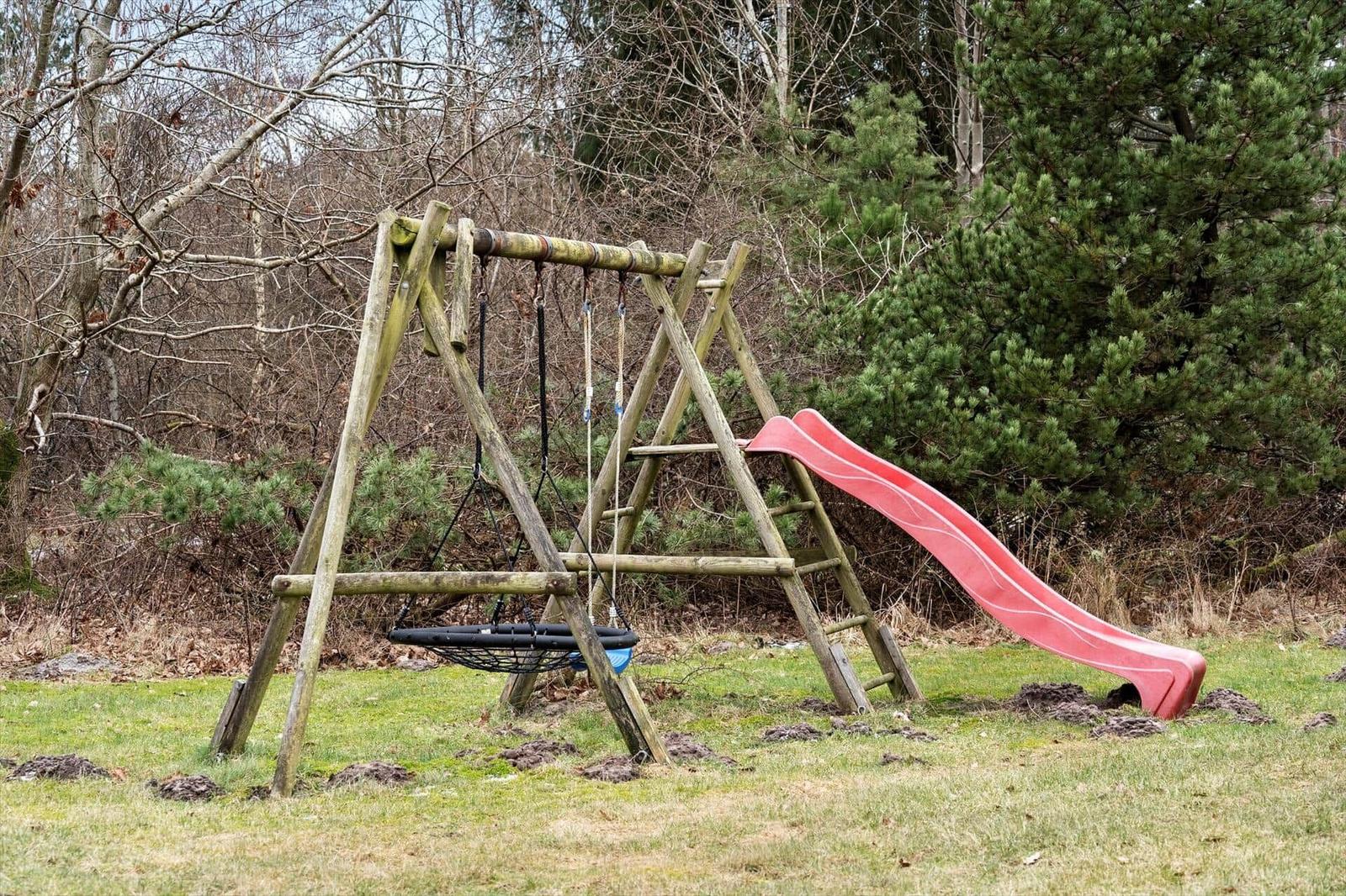 Holzschaukel mit rotem Rutschbahn im Garten