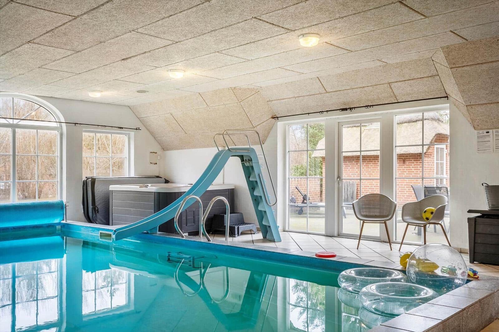 Indirekter Pool mit Rutsche und Sitzgelegenheiten im Inneren.