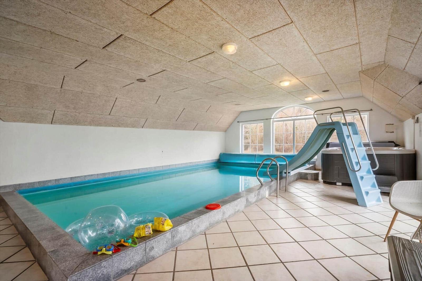 Indirektes Licht beleuchtet den Innenpool mit Rutsche und Spielzeug.