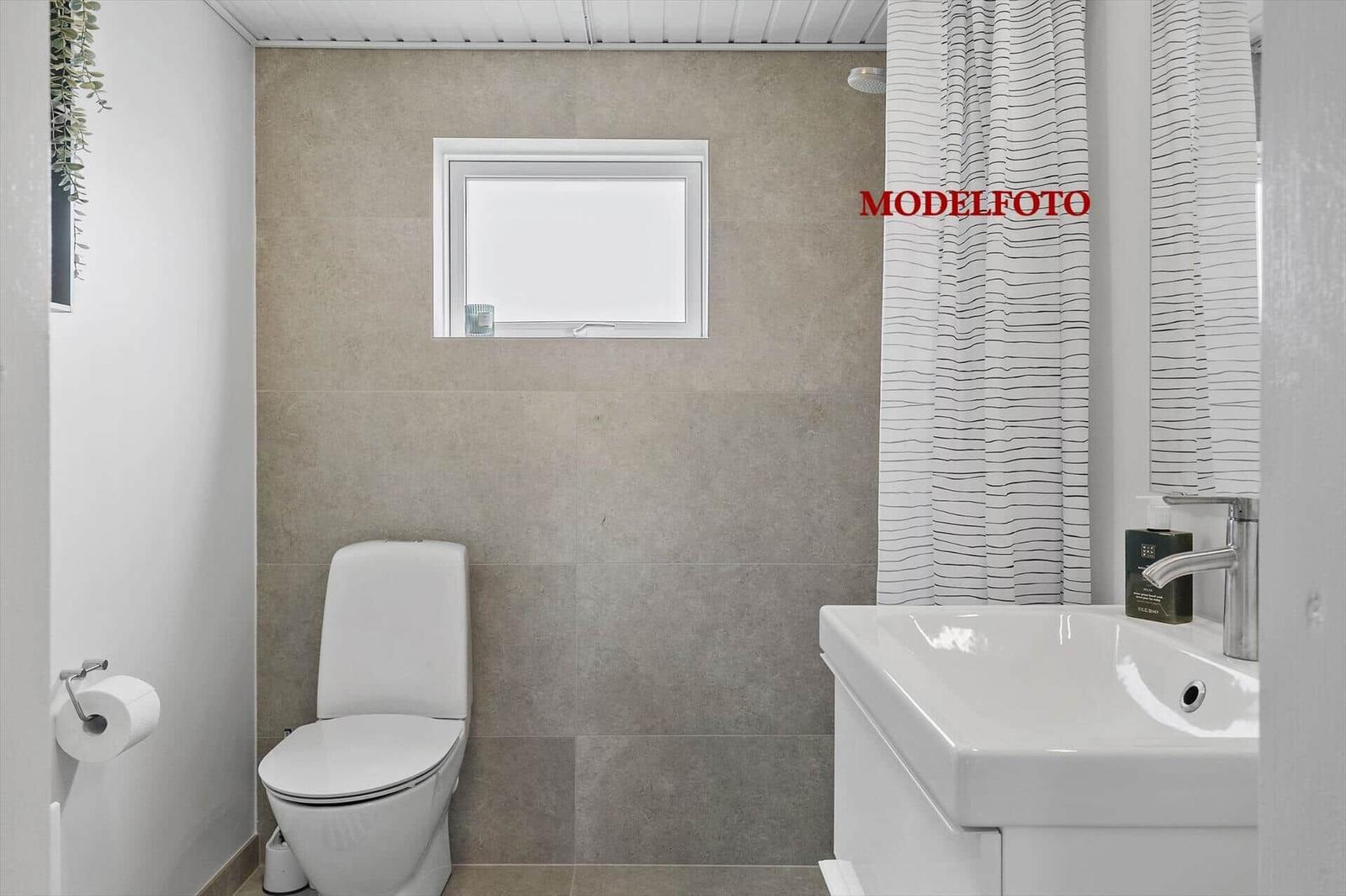 Badezimmer mit Toilette, Waschbecken und Dusche mit Vorhang.