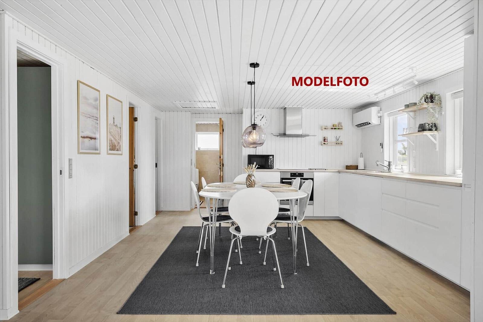 Küche mit Esstisch, weiße Schränke und Holzboden