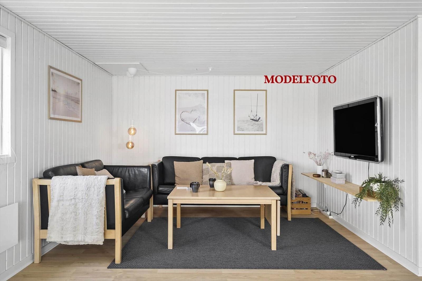 Wohnzimmer mit Sofa, Couchtisch und Wandfernseher.
