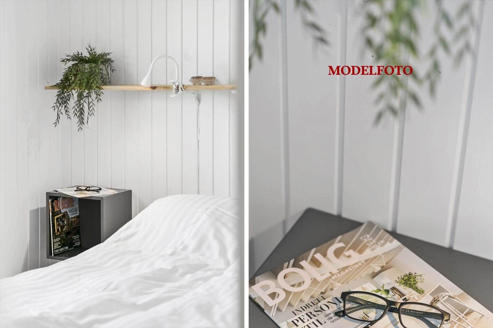 Schlafzimmer mit weißer Wand, Bett, Nachttisch und Pflanze.