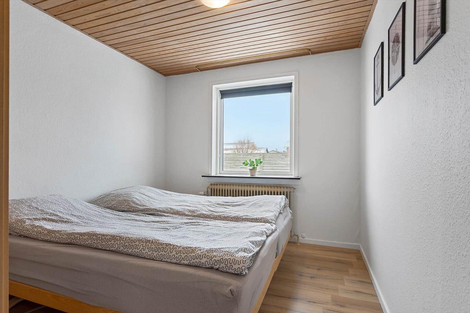 Bedroom with bed, window, and wooden floor.