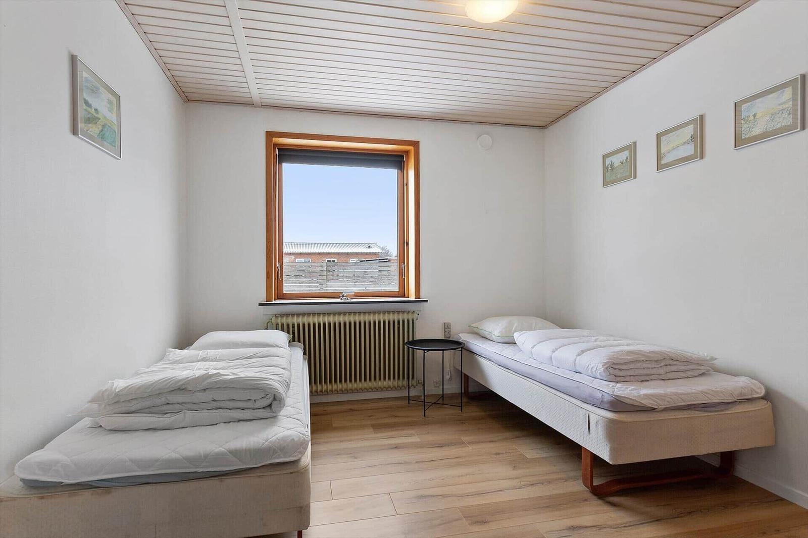 Two beds, window, wall pictures, wooden floor, ceiling with wooden beams