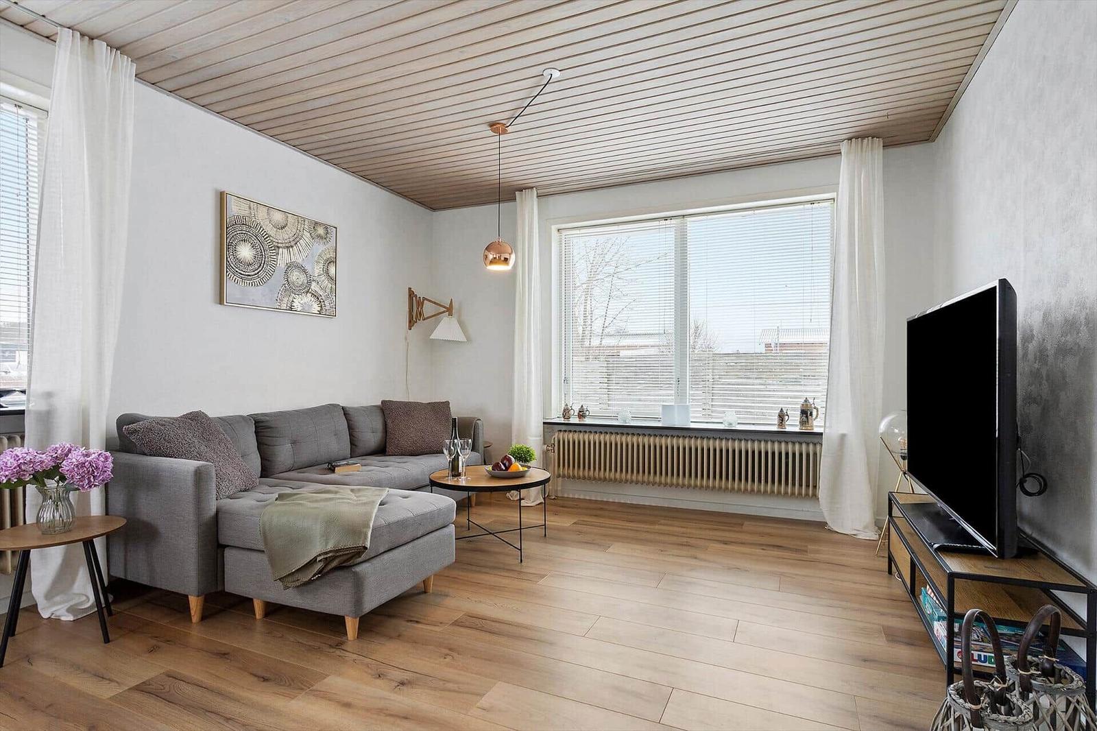 Living room with sofa, TV, and wooden floor.