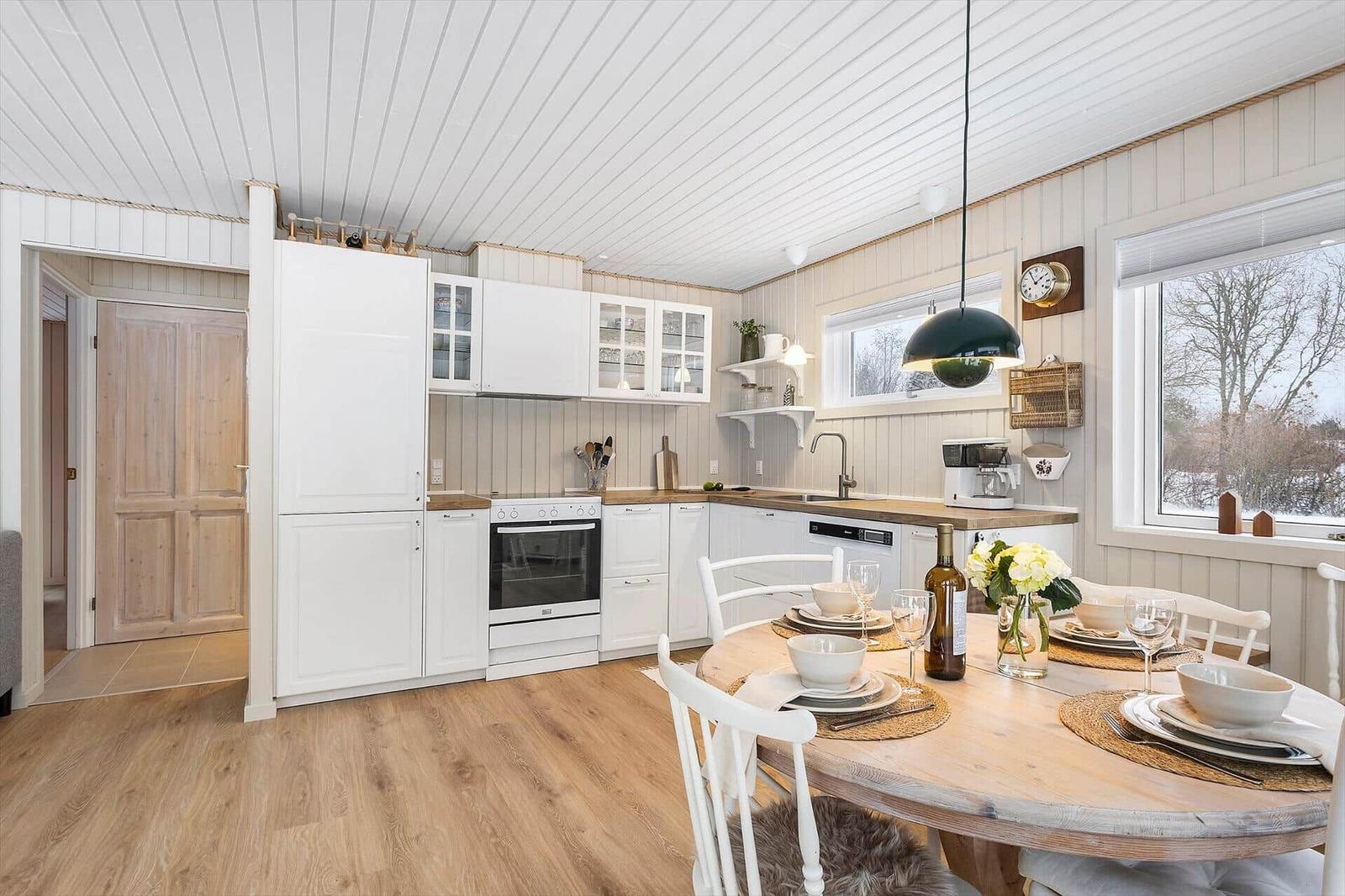 Kitchen with dining area, white cabinets, and wooden floor. Table set with flowers.