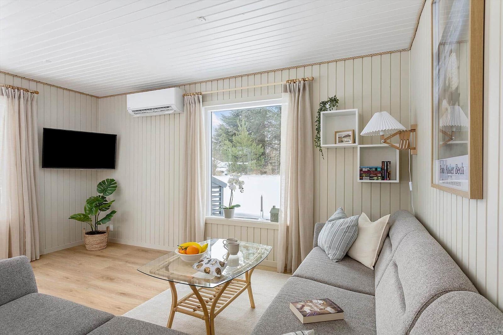 Living room with sofa, glass table, and TV mounted on the wall.