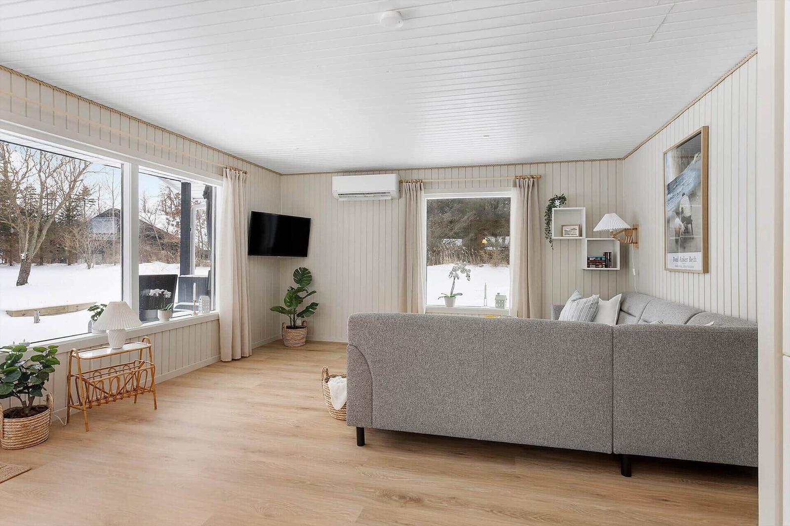 Living room with sofa, TV, and large windows for views.