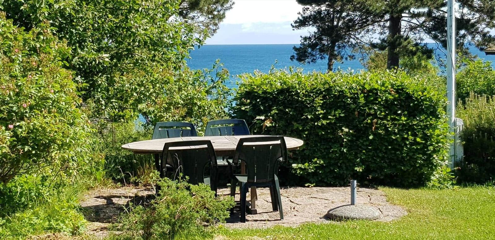 Rundtisch mit Stühlen im Garten mit Blick auf das Meer