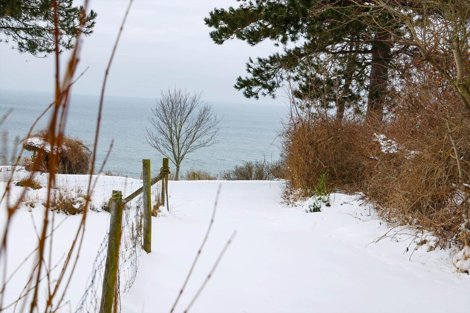 Schneebedeckter Weg führt zu einem Blick auf das Meer.